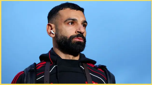 Mo Salah wears headphones and looks on.